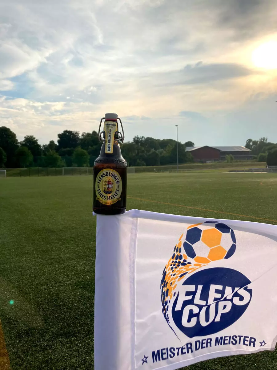 Bierflasche Flensburger Edles Helles auf einer Flagge mit dem Logo vom FLENS CUP Meister der Meister.