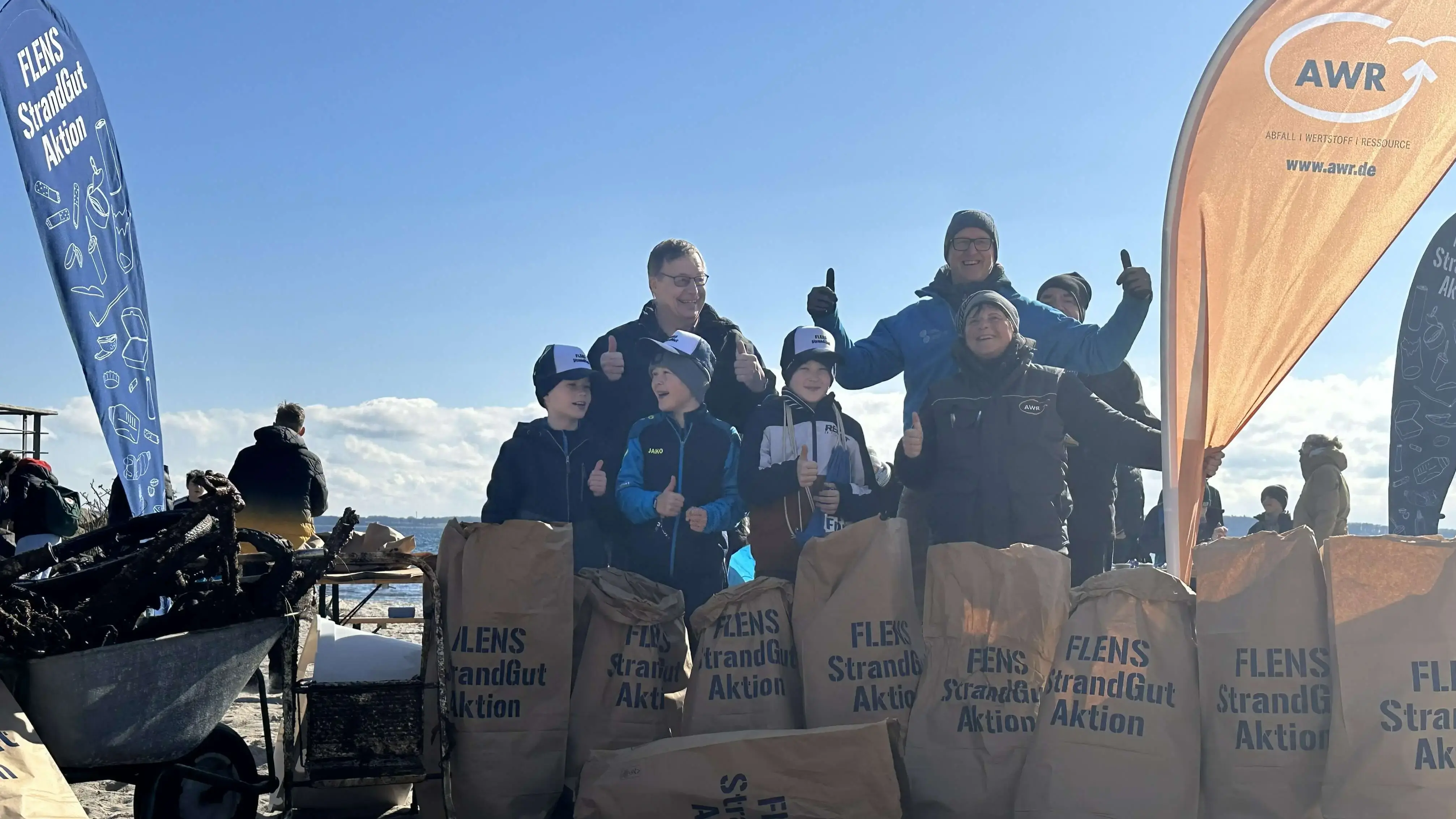 Gruppe von Freiwilligen bei einer FLENS Strandreinigungsaktion mit Müllsäcken.