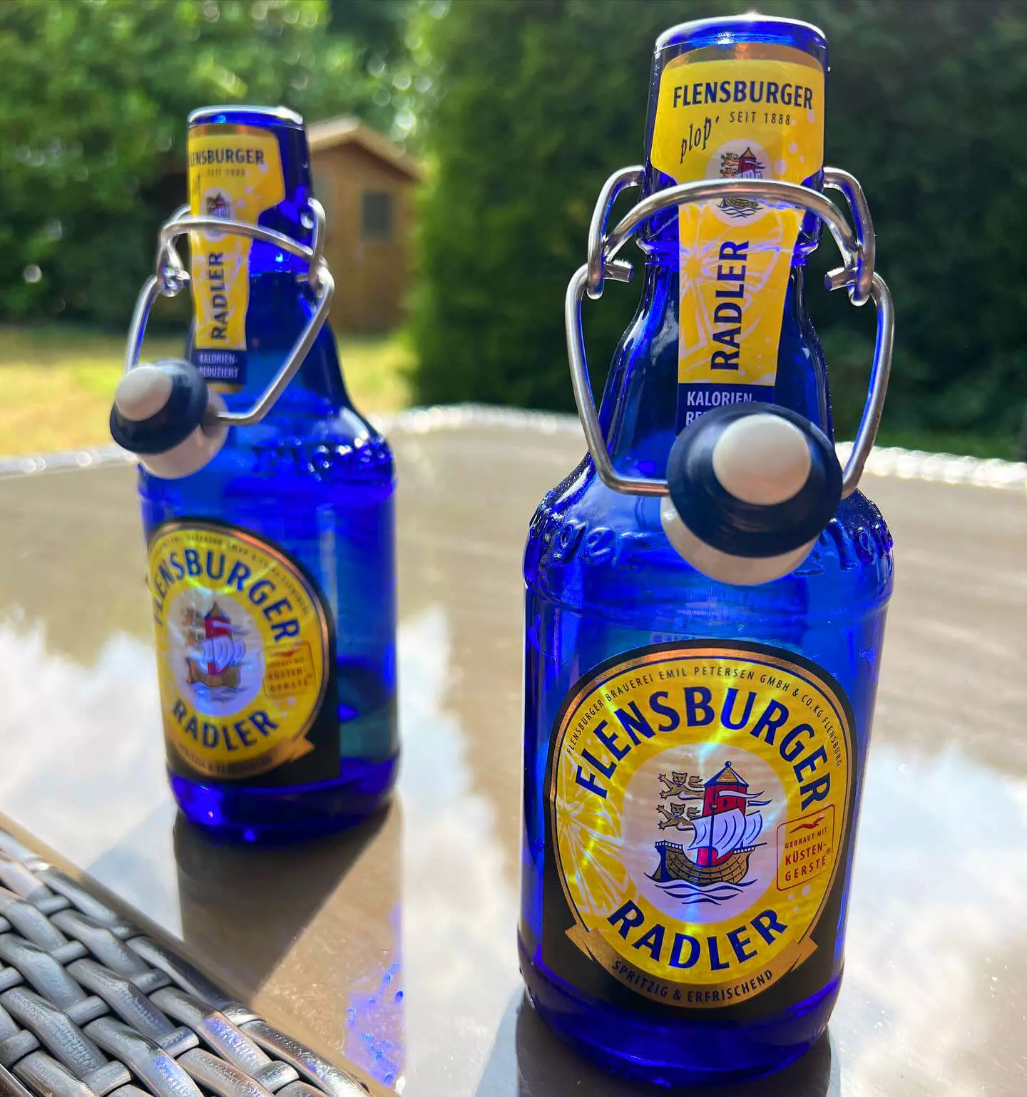 Zwei geöffnete blaue Flaschen Flensburger Radler auf einem Tisch.