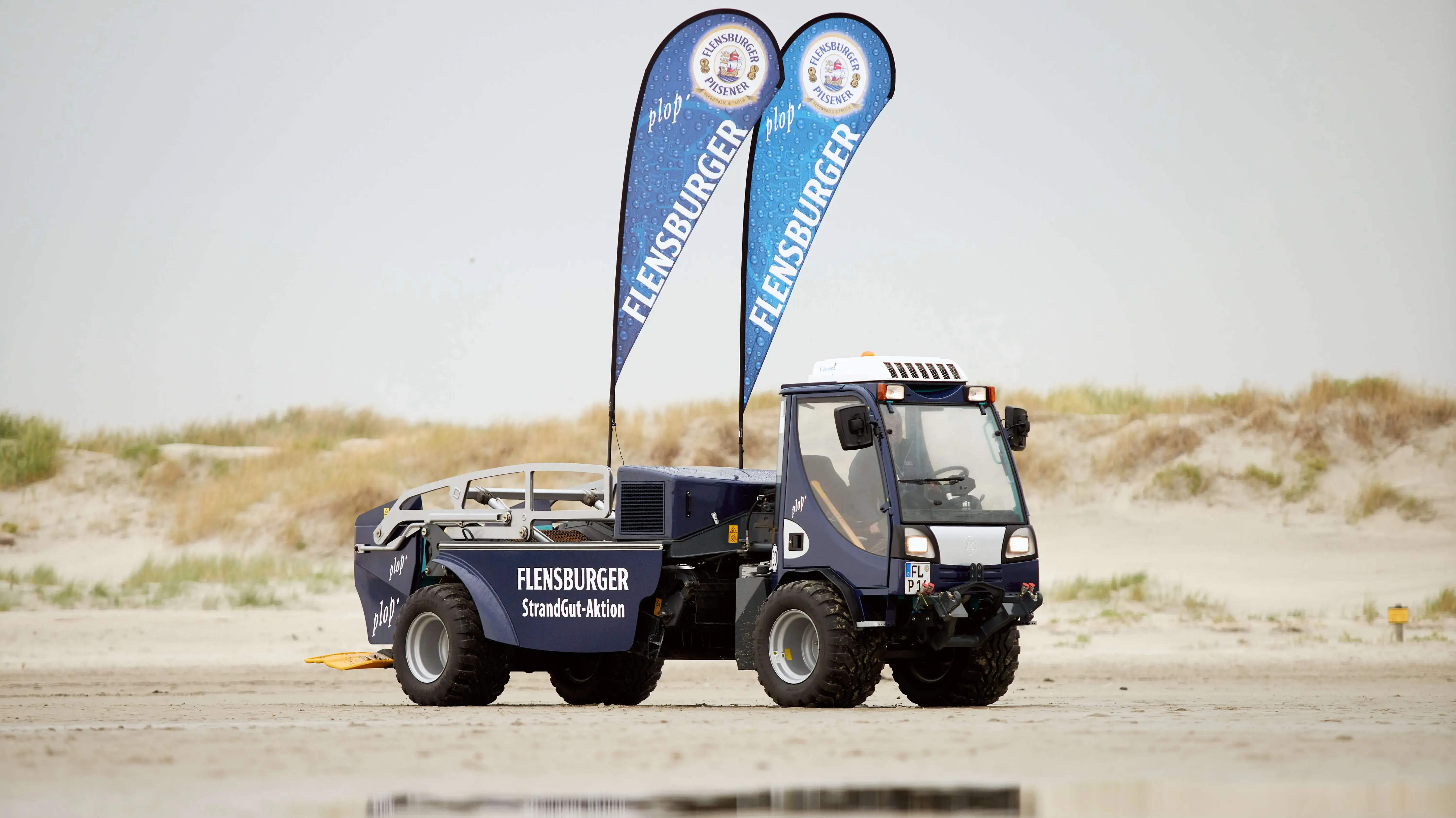 FLENS Beach Tech mit Flaggen am Strand für Strandreinigungsaktion.