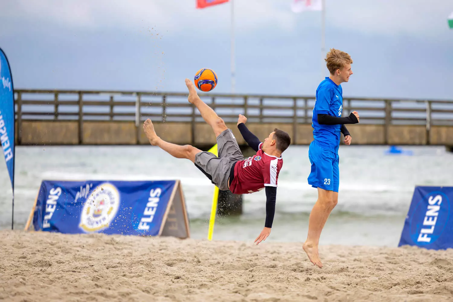Teilnehmer des FLENS Beach Trophy Turniers am Strand bei einer Flanke.