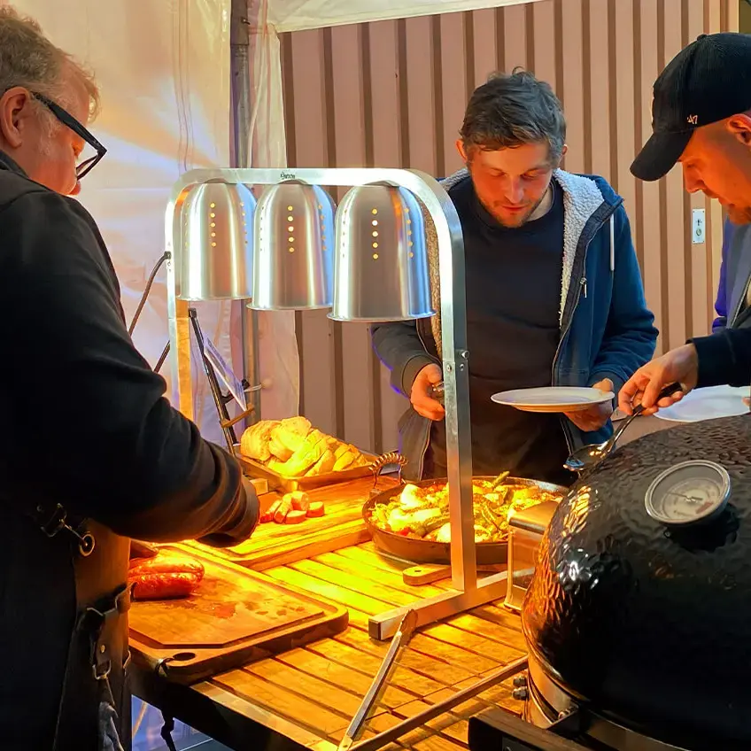 Die Gewinner bedienen sich an der Vorspeise bei der Grillweltmeisterparty von FLENS, rechts der große Kugelgrill von Grillweltmeister Marco Greulich, links im Bild.