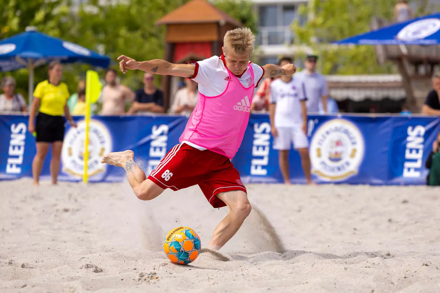 Teilnehmer des FLENS Beach Trophy Turniers am Strand, mitten im Schuss.