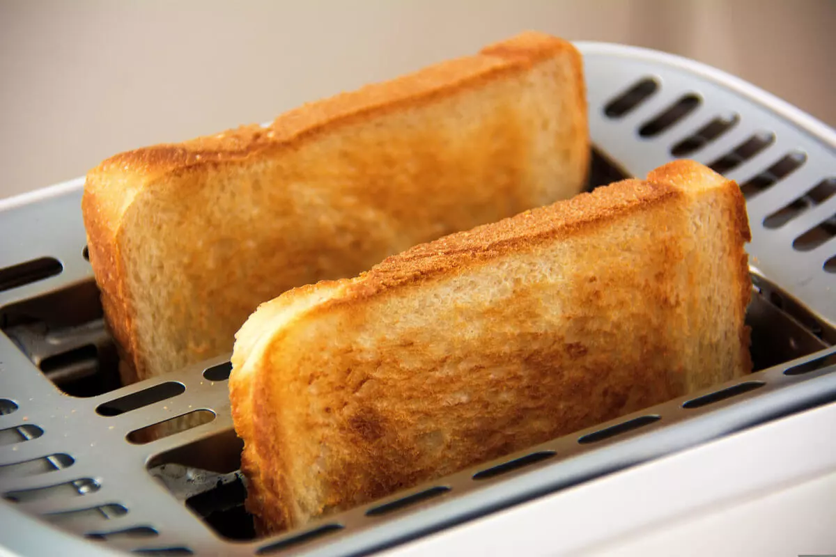 Zwei geröstete Toastscheiben kommen aus den Toasterschlitzen.