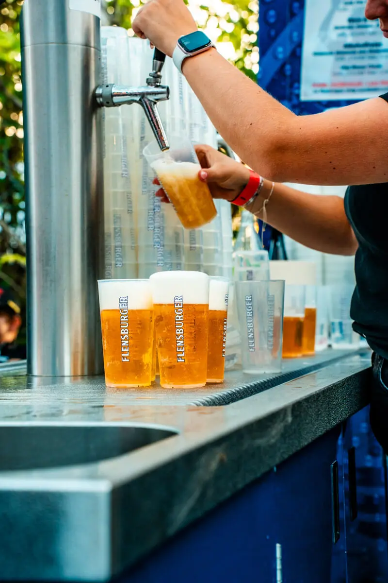 Servicekraft auf dem FLENS Festival 2025 beim Zapfen vom Flensburger Bier.