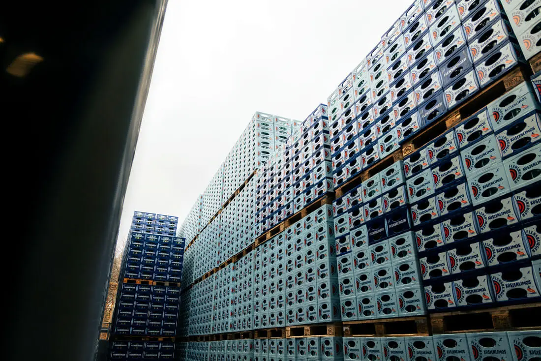 Hochgestapelte blaue Getränkekisten auf Paletten im Außenlager bei FLENS.