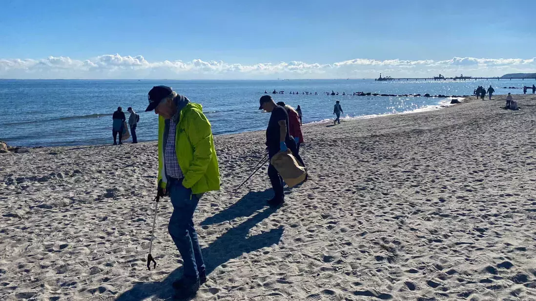 Helfer in Aktion bei der FLENS StrandGut-Mitmachaktion in Grömitz 2024 am Strand.