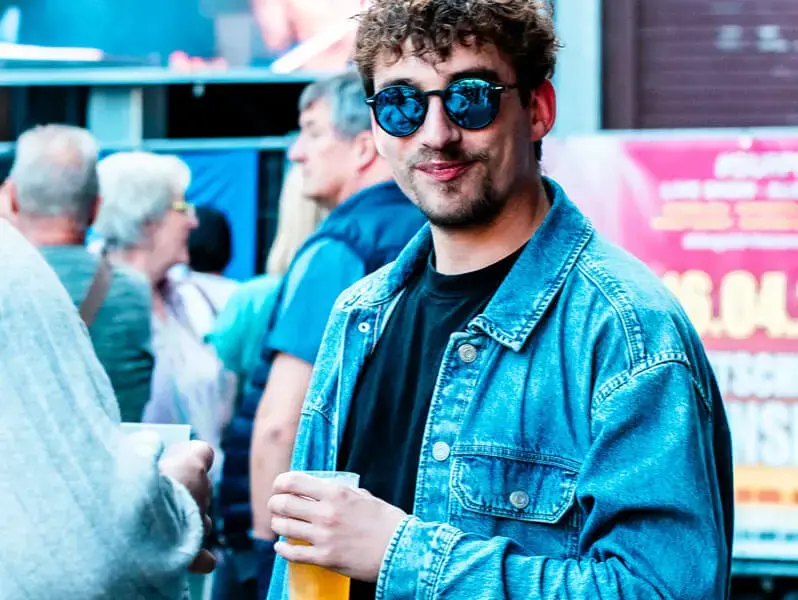 Mann mit Sonnenbrille trinkt Bier beim FLENS Festival 2025.