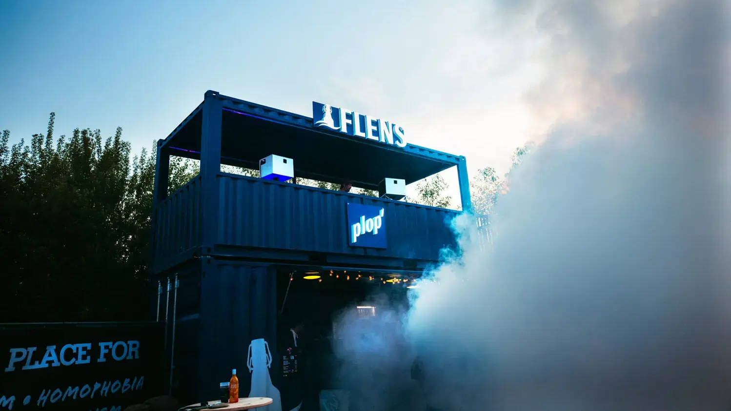 Blaue Container-Eventbar mit 'FLENS'-Schild, 'plop'-Logo und dichtem Nebel beim Butcher-Jam-Festival 2026.