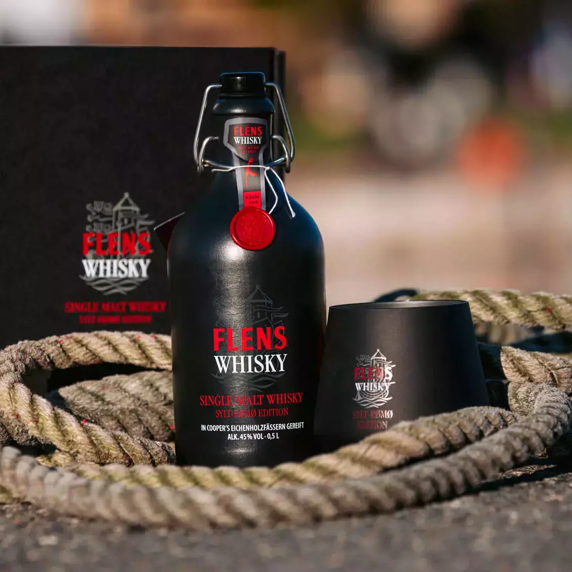 Das FLENS Whisky Set, bestehend aus der schwarzen Tonflasche, einem schwarzen Whisky-Becher und einem dazu passenden Karton in maritimen Dekor.