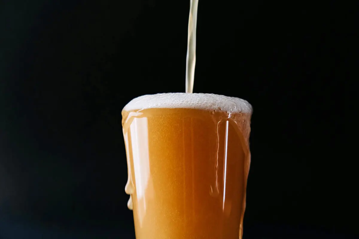 Ein naturtrübes Ale wird in ein Glas eingeschenkt, schwarzer Hintergrund.