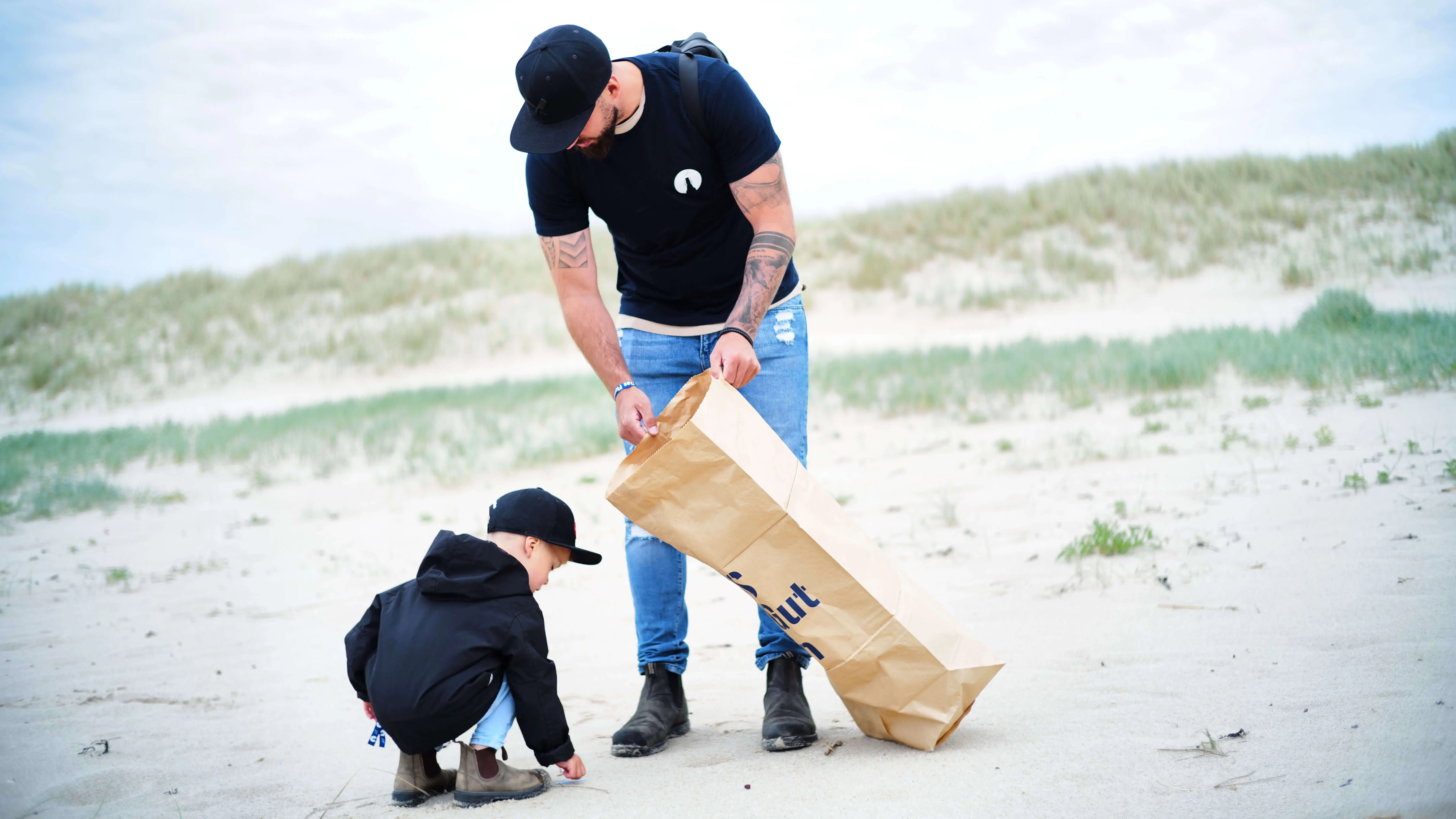 Vater und Kind sammeln Müll am Strand bei einer FLENS Strandreinigungsaktion.