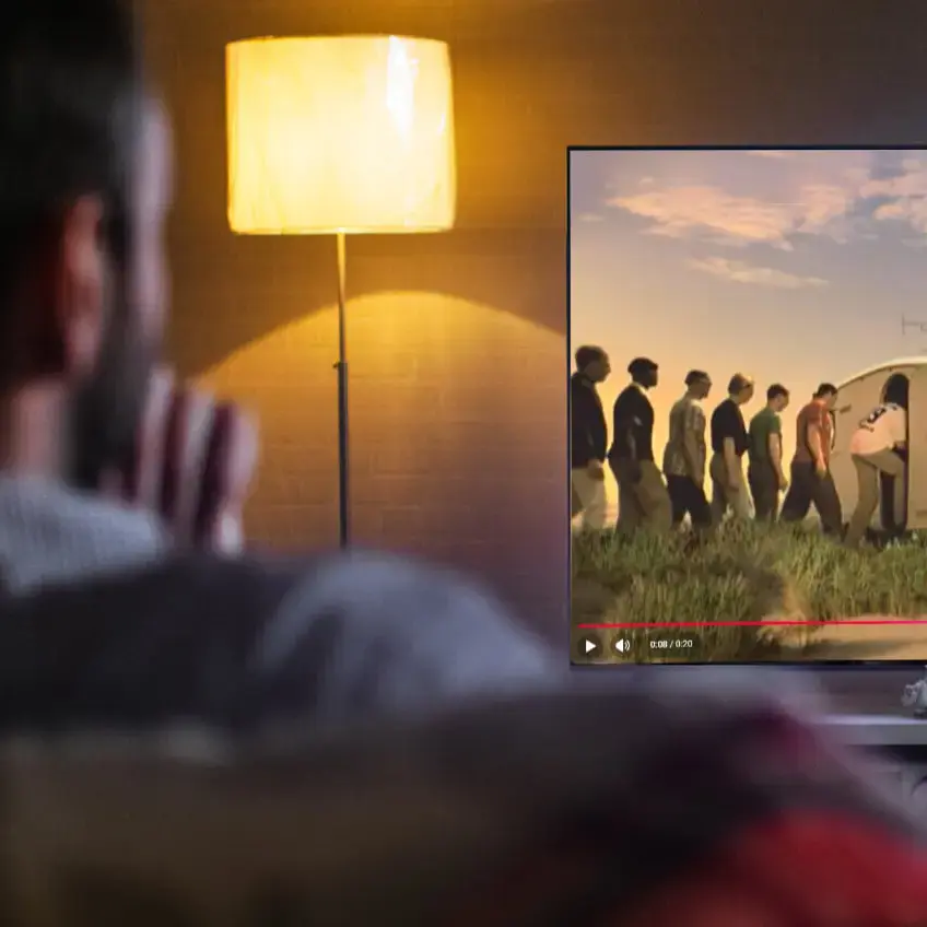 Ein Mann schaut im Wohnzimmer eine alte Flensburger-Werbung auf YouTube an.