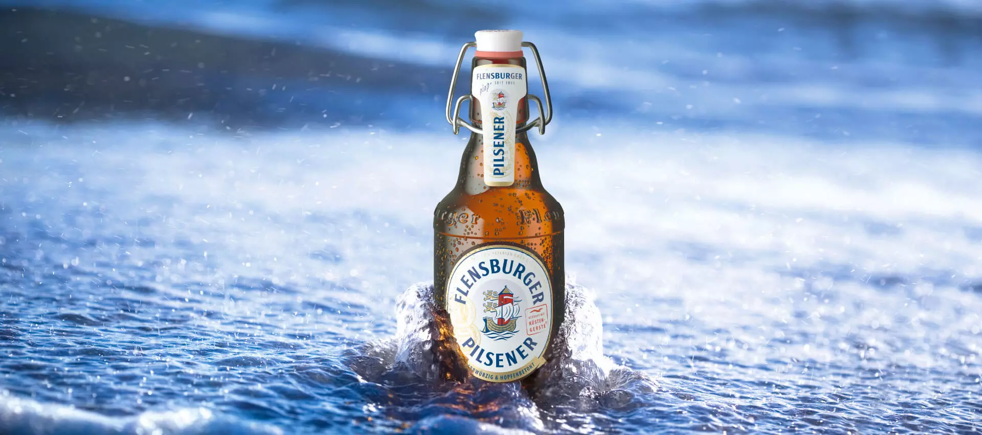 Flasche Flensburger Pils in der Brandung im Wasser.