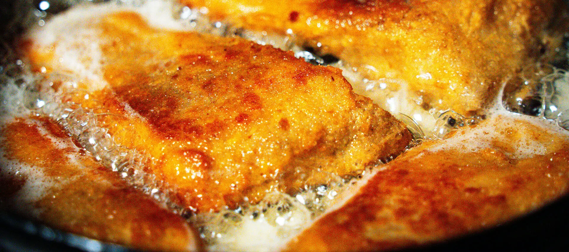 Goldbraun panierter Backfisch wird in sprudelndem Öl gebraten.