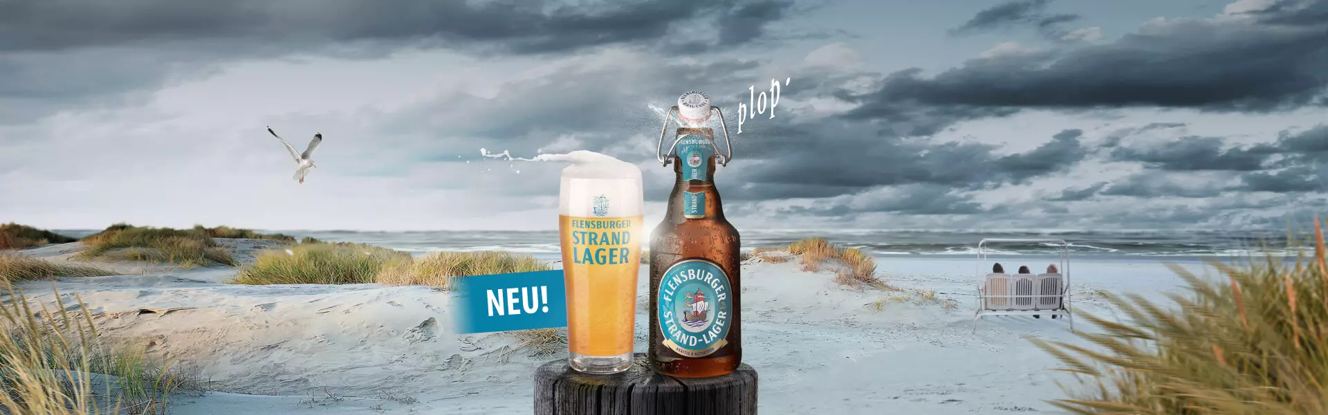Flensburger Strand-Lager mit Glas vor stürmischer Strandkulisse.