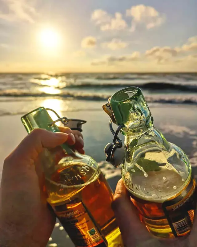 Es wird mit zwei Flaschen Flensburger Gold vorm Sonnenuntergang am Strand angestoßen.