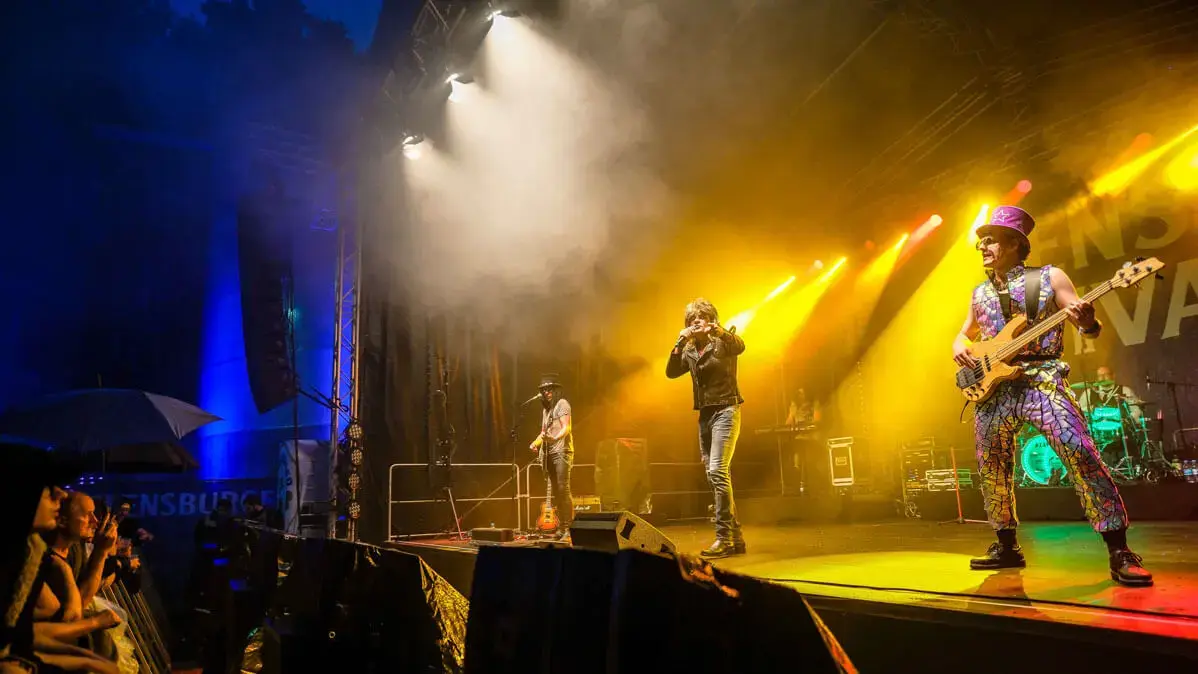 Die kostümierte Coverband "Hit Radio Show" auf der Bühne beim FLENS Festival 2023.