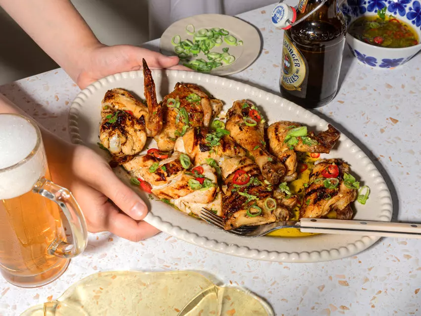 Teller mit Grillhähnchen in Biermarinade, im Hintergrund ein Flensburger Edles Helles.