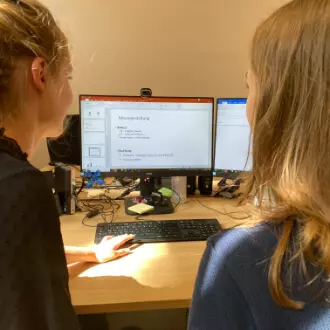 Zwei Frauen an einem Schreibtisch mit PC