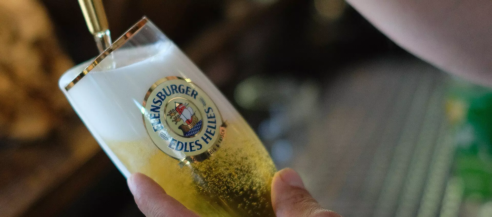 Flensburger Edles Helles wie es, in einem FLENS Edles Helles Glas, gezapft wird.