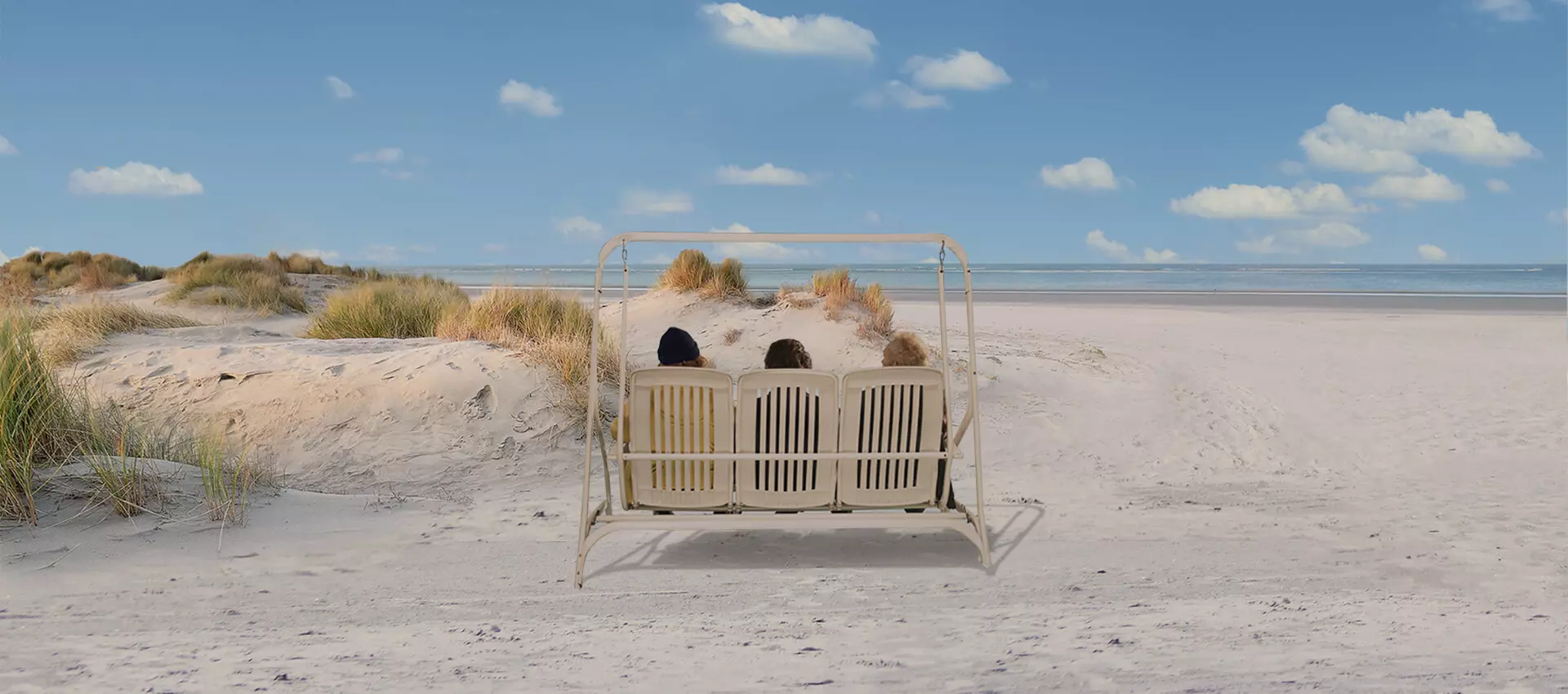 Drei Männer auf einer Schaukel am Strand.