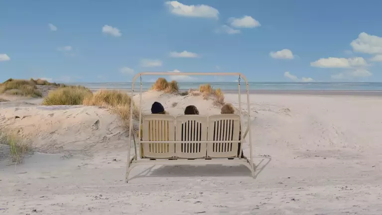 Drei Männer auf einer Schaukel am Strand.