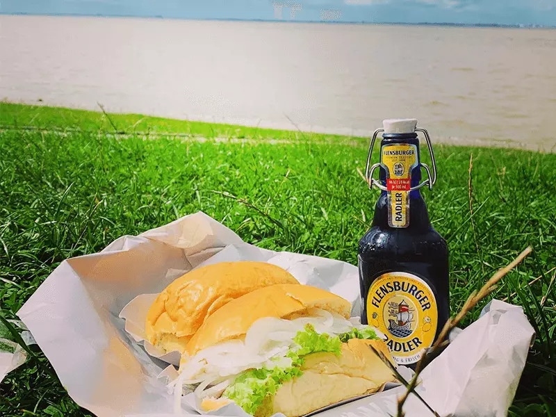 Flensburger Radler mit Fischbrötchen am Strand.