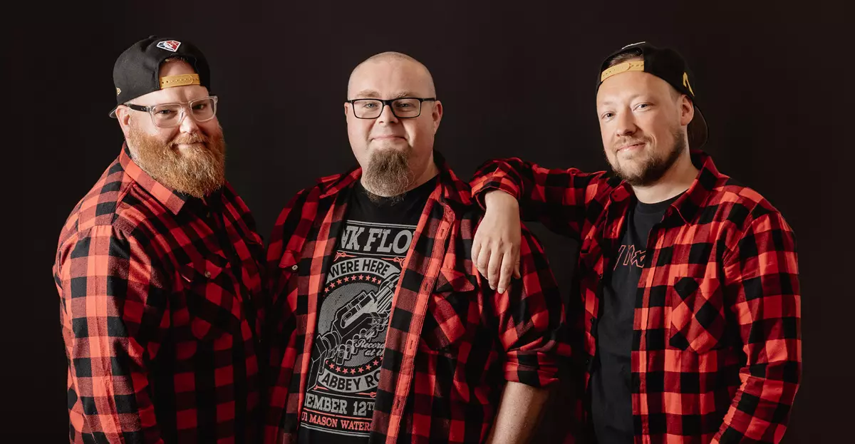 Pressebild der Coverband Die Andersons: Drei Männer im Karohemd vor schwarzem Hintergrund.