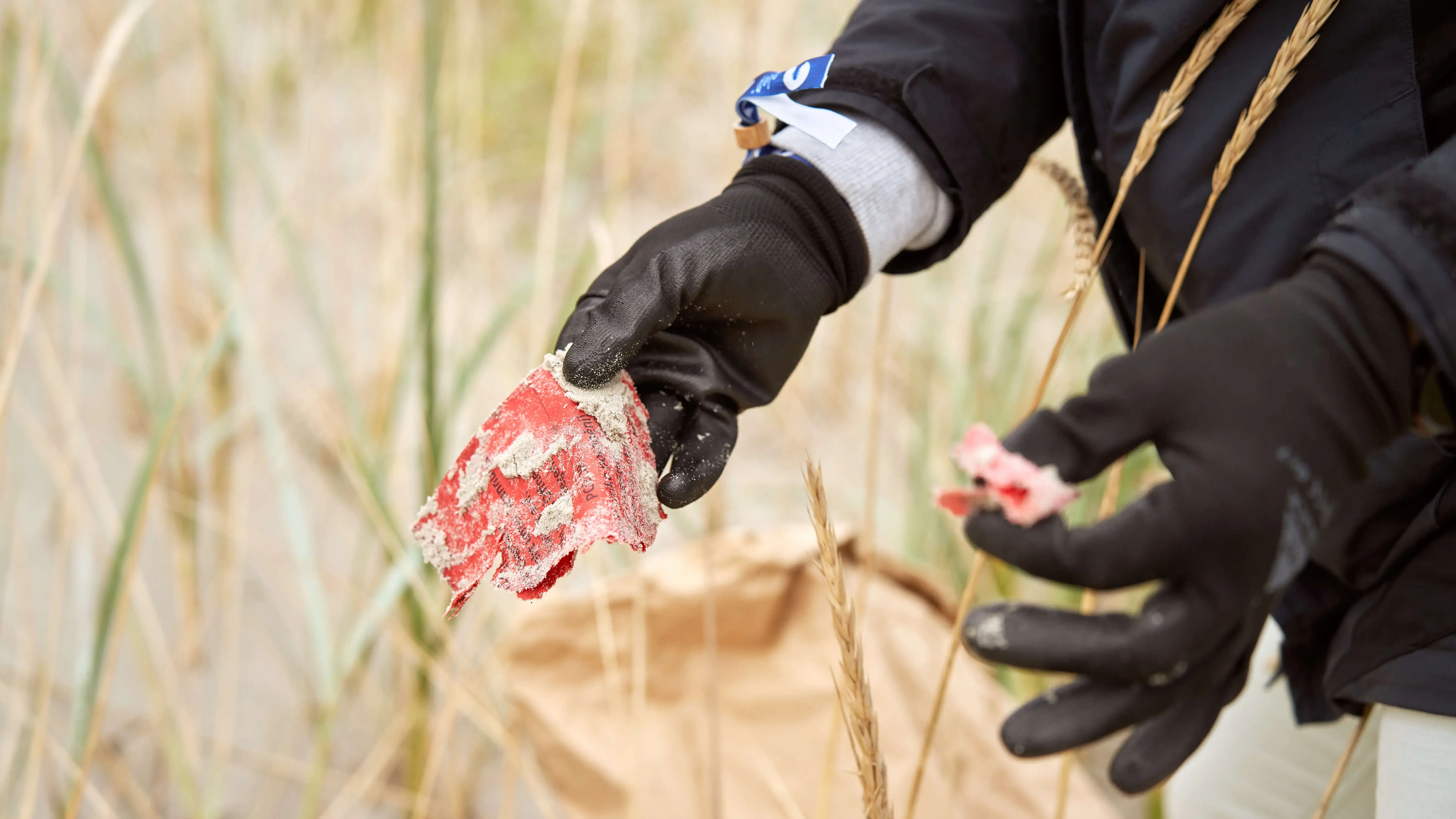 Person sammelt Plastikmüll am Strand zur Umweltschonung.