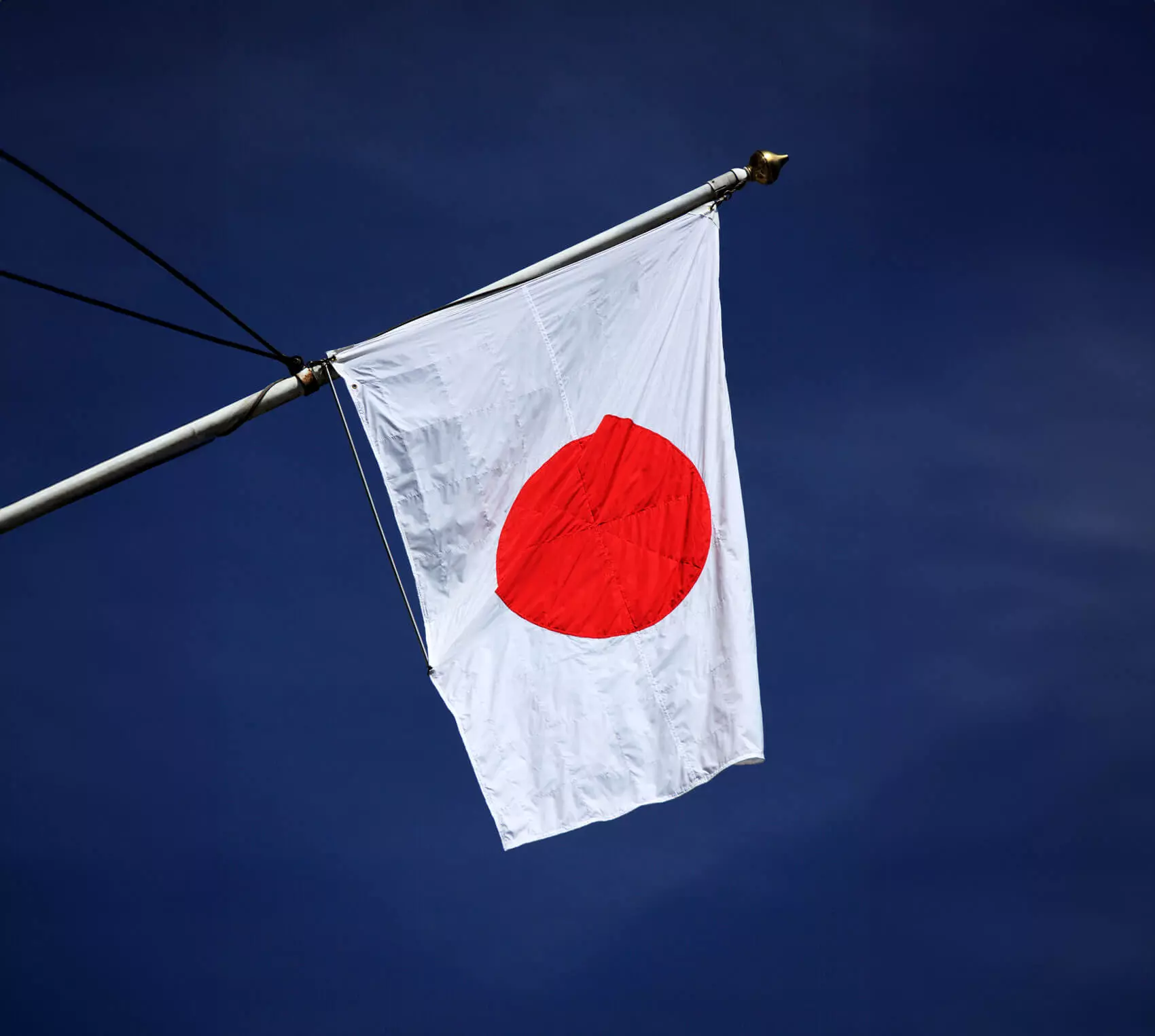 Die gehisste Flagge Japans vor blauem Himmel.