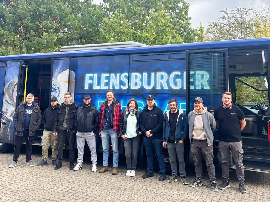 Die Gruppe des glücklichen Gewinners und seiner 11 Freunde vor der Flensburger Fahrbar an einem bewölkten Tag.