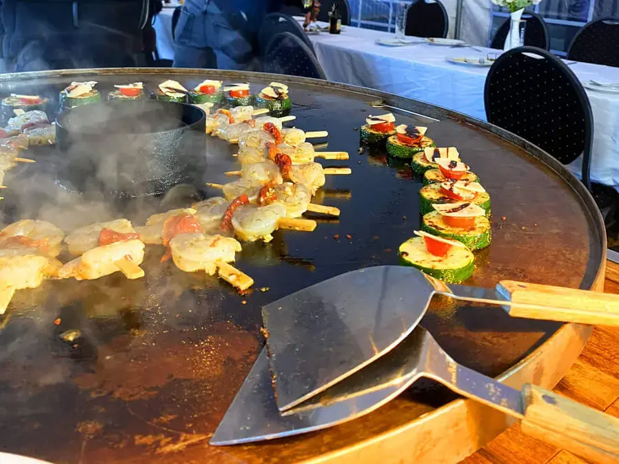 Appetitlich aussehende, dampfende Scampi-Grillspieße bei der Grillweltmeisterparty von FLENS mit Gästen.