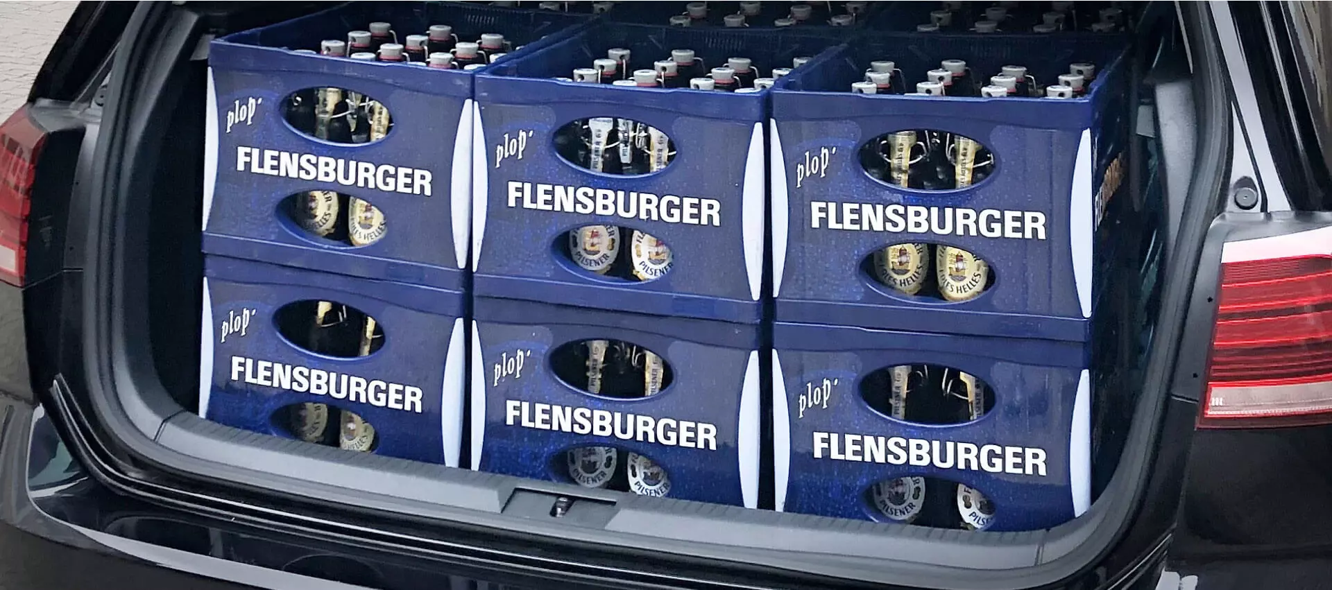 Offener Kofferraum mit 6 Kisten Flensburger Getränken beladen.