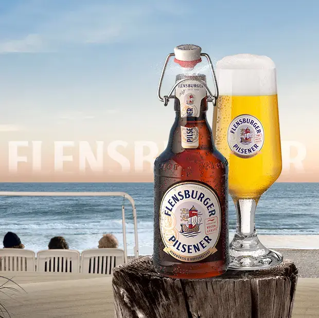 Beach scenery with wooden pole in the foreground, carrying a bottle and a glass of Flensburger Pilsener beer.