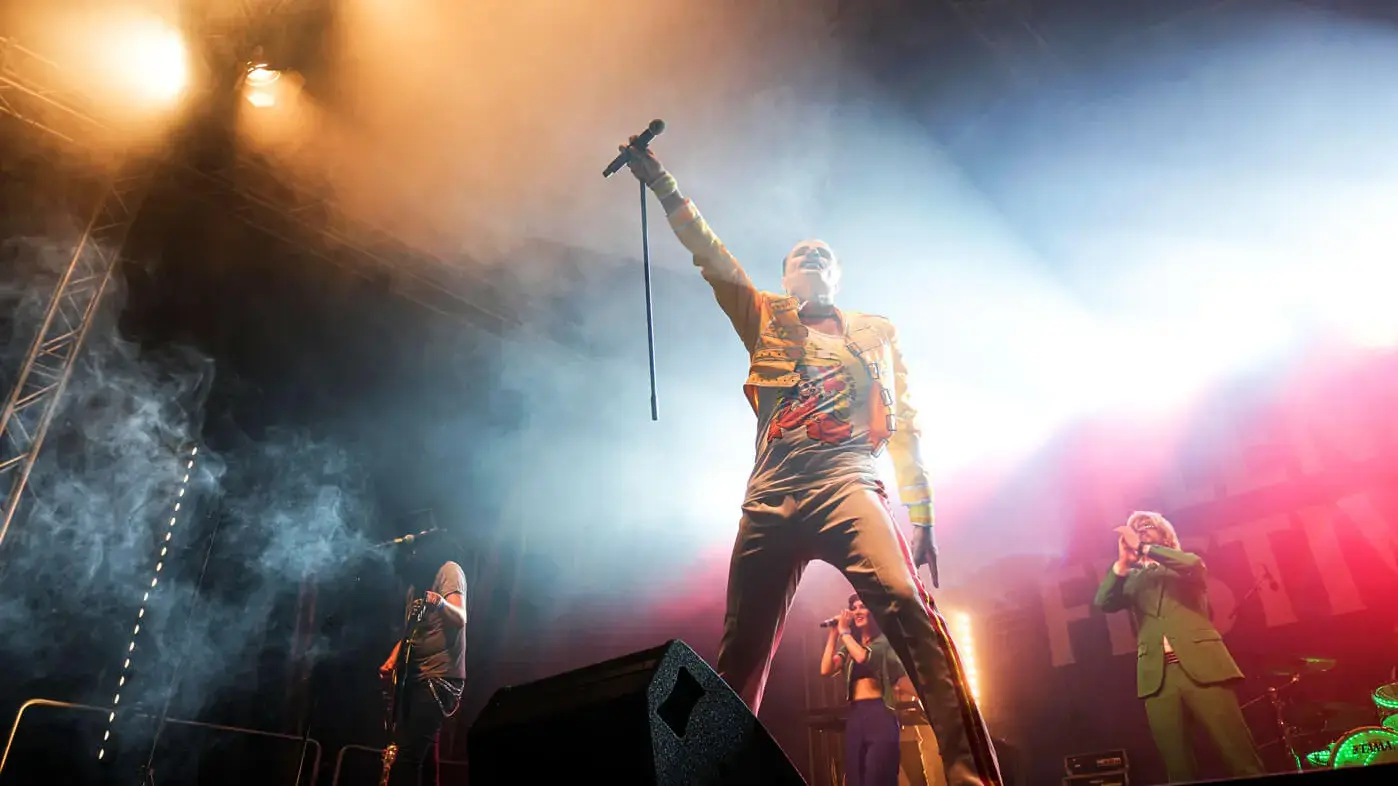 Die Coverband "Hit Radio Show" auf der Bühne beim FLENS Festival 2023 mit einer Freddie-Mercury-Imitation.