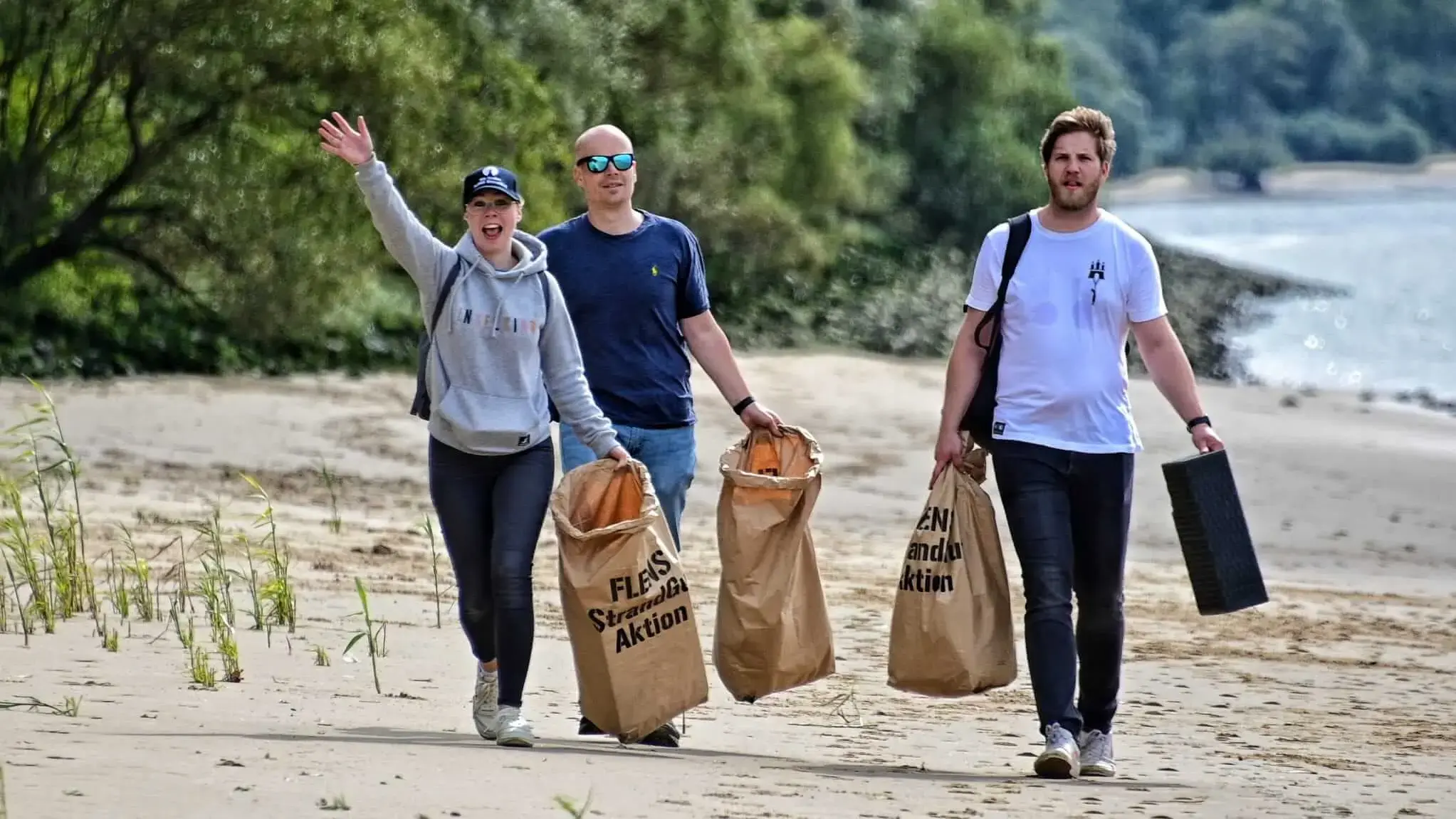 Gruppe von Freiwilligen bei einer FLENS Strandreinigungsaktion mit Müllsäcken.