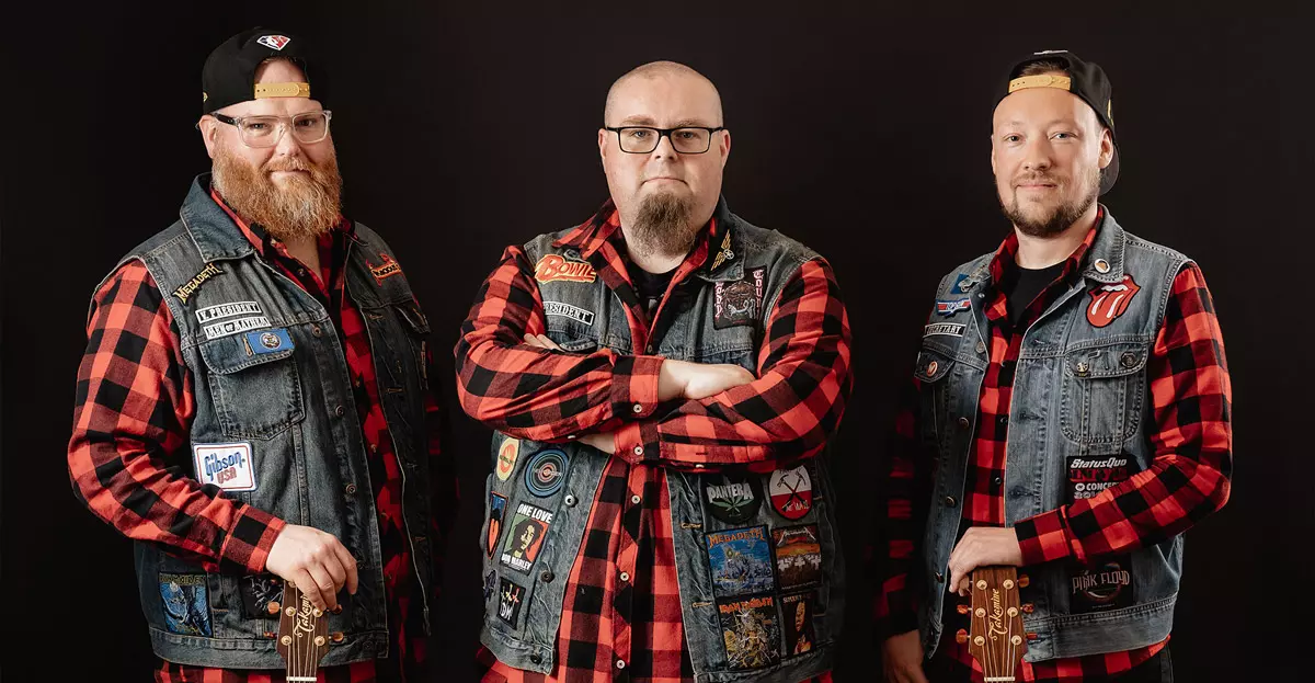 Pressebild der Coverband Die Andersons: Drei Männer im Karohemd und Jeanswesten vor schwarzem Hintergrund.