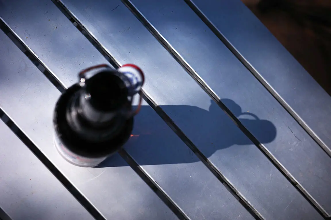 Draufsicht: Flasche mit Bügelverschluss auf Aluminiumtisch mit langem Schatten