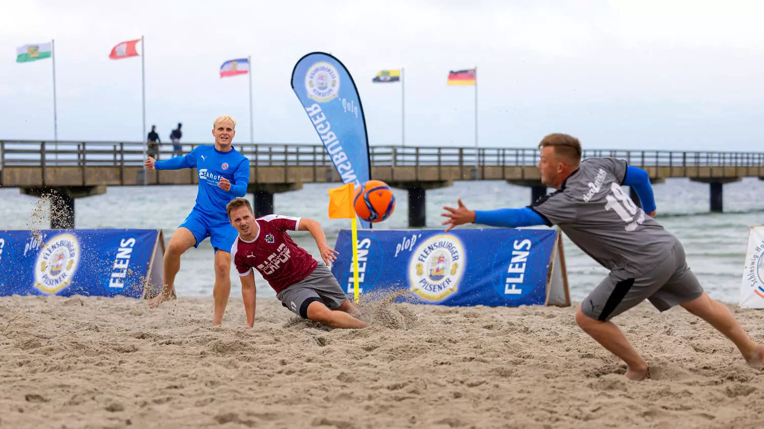 Teilnehmer des FLENS Beach Trophy Turniers am Strand bei einem Torschuss.