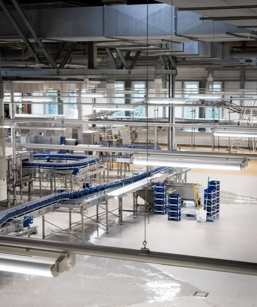 Moderne Flaschenabfüllanlage mit blauen Glasflaschen auf Förderbändern in der Flensburger Brauerei.