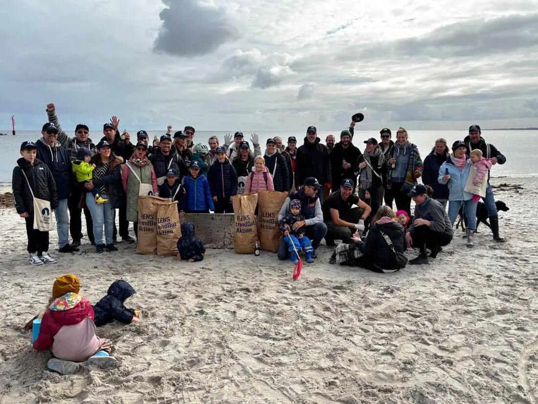 Gruppe von Freiwilligen bei einer FLENS Strandreinigungsaktion am Strand.