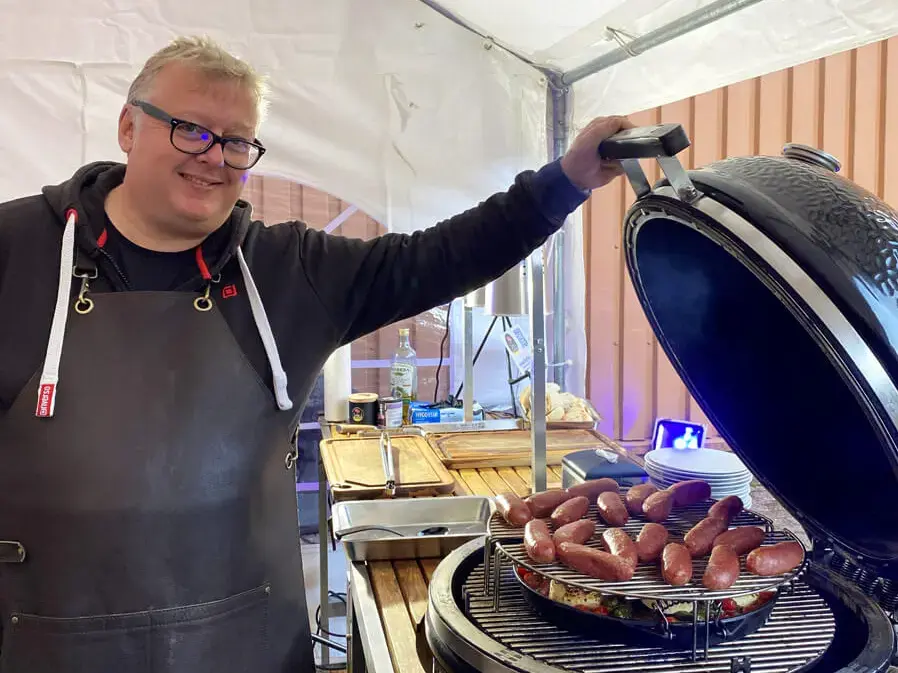 Grillweltmeister Marco Greulich öffnet den großen Outdoor-Kugelgrill mit Salciccia-Würstchen bei der Grillweltmeisterparty von FLENS.