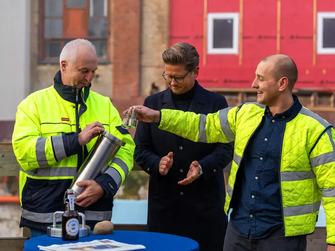 Die Geschäftsführer der Flensburger Brauerei und der erste Braumeister befüllen die Zeitkapsel mit Hopfen und Malz.