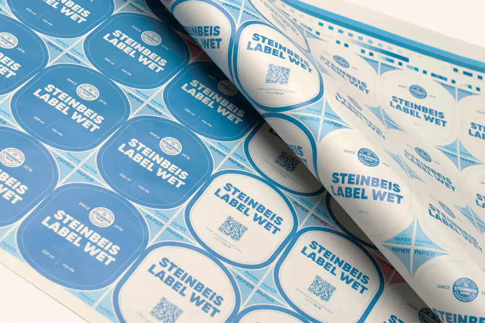 Blau-weiße Etiketten mit der Aufschrift 'Steinbeis Label Wet' mit QR-Codes auf einem Druckbogen.