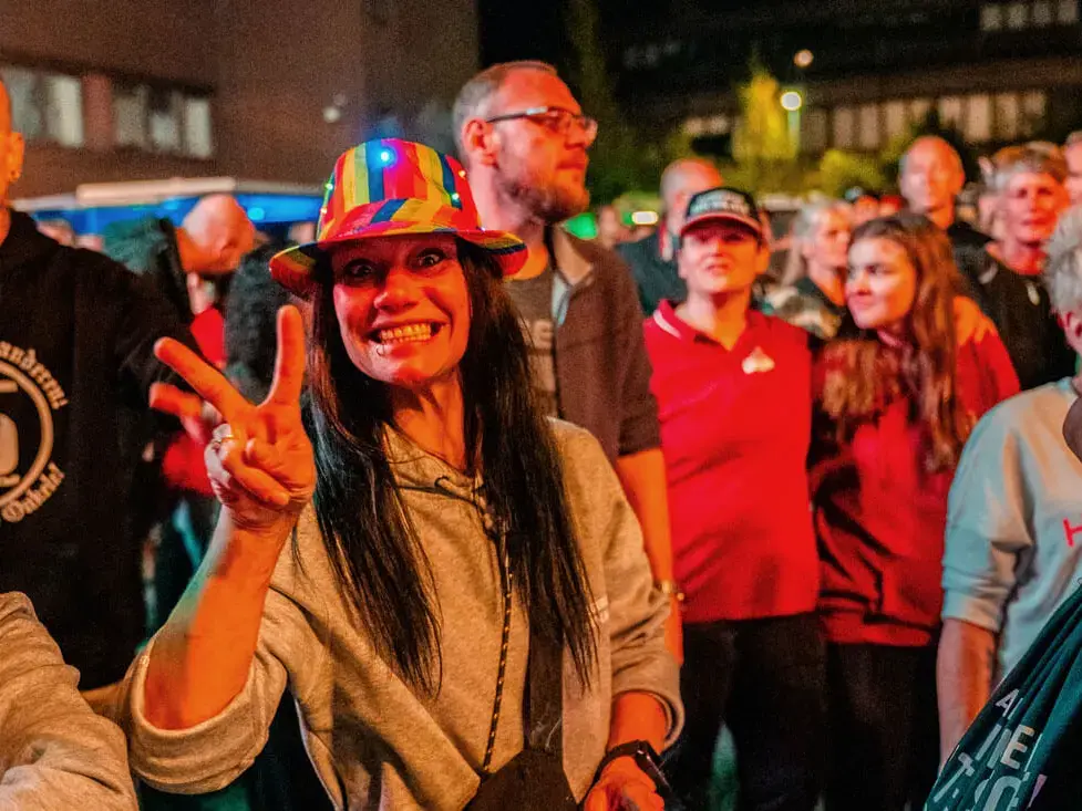 Fröhliche Frau im Publikum beim FLENS Festival 2025 zeigt das Piece-Zeichen.