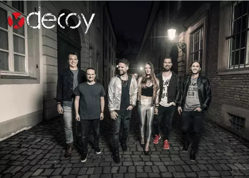 Pressefoto der Coverband DECOY mit Logo oben links in der Ecke: 6 Bandmitglieder laufen auf der Straße.