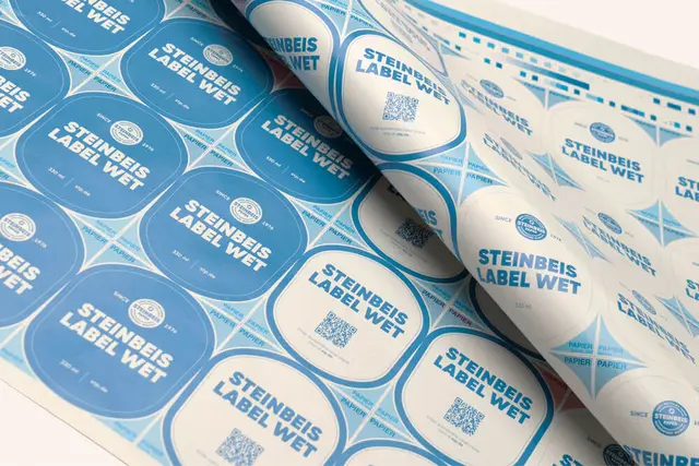 Blau-weiße Etiketten mit der Aufschrift 'Steinbeis Label Wet' mit QR-Codes auf einem Druckbogen.