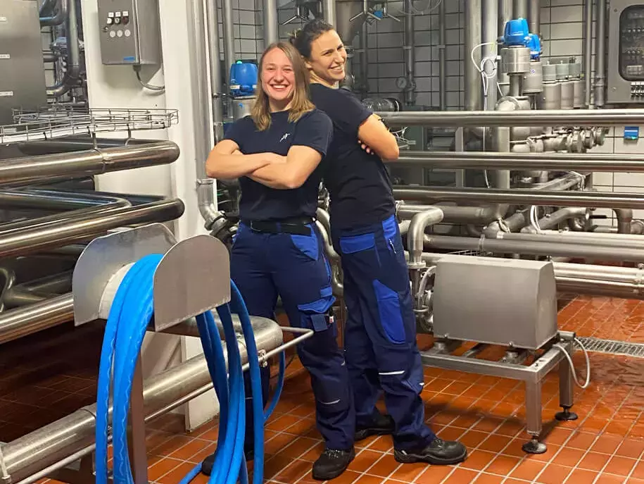 Die Brauerinnen Lisa & Karolin von FLENS stehen Rücken an Rücken im Gärkeller.