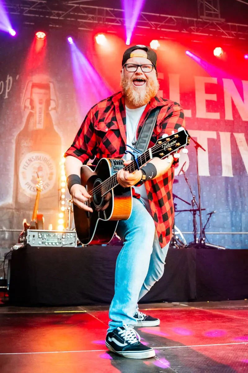 Mitglied der Partyband Die Andersons an der Gitarre auf dem FLENS Festival 2025.